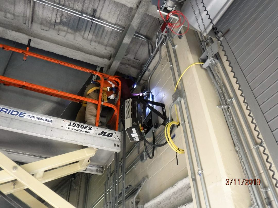 An electrician installing electrical conduit in a commercial power sub-station